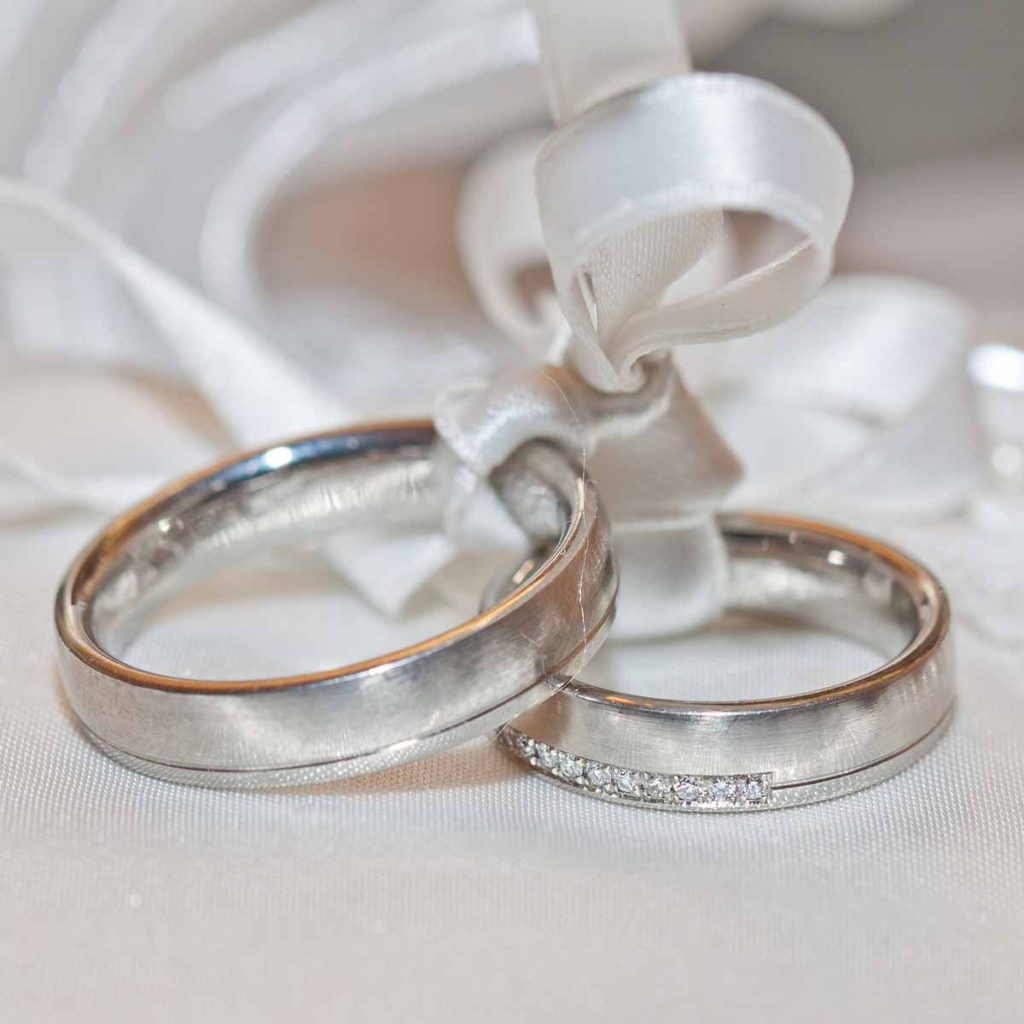 Closeup of silver wedding rings with satin rope